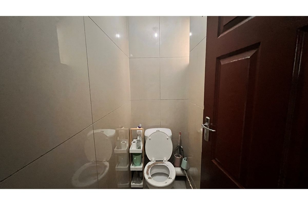 A compact bathroom featuring full-height wall tiling and a standard toilet fixture.