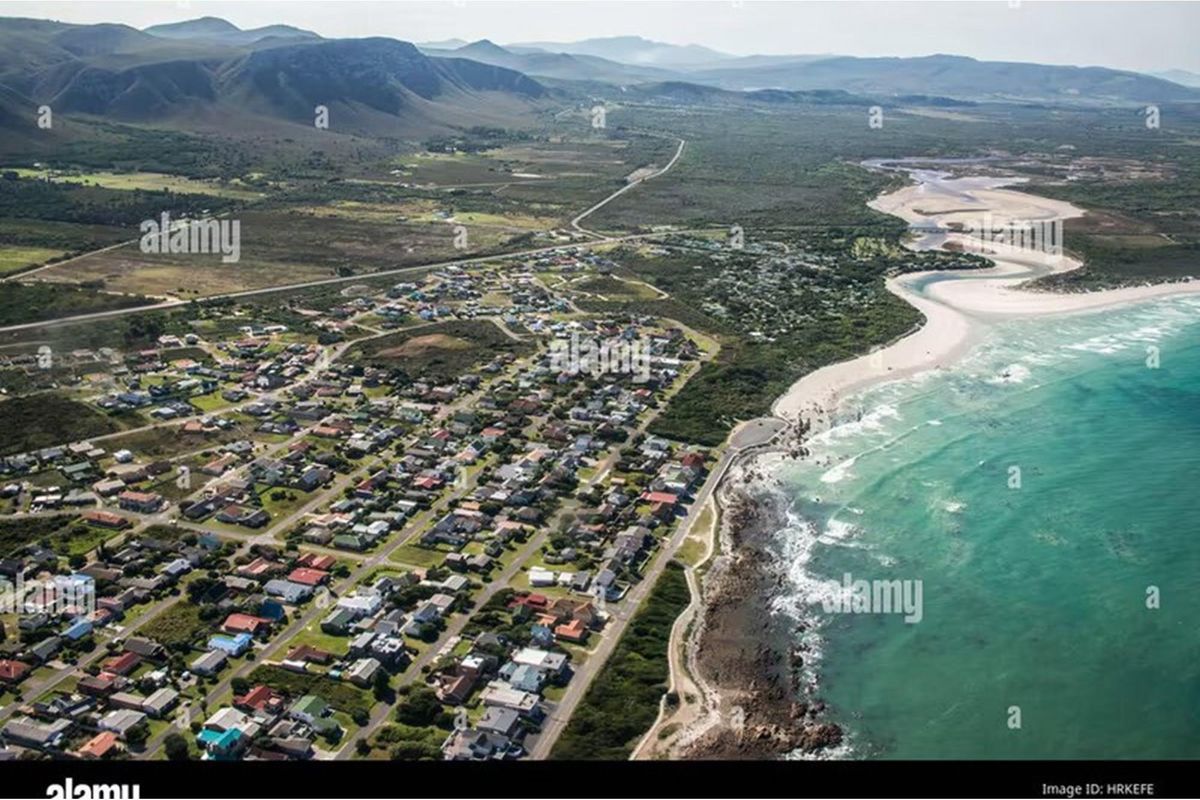 Aerial view of a coastal residential neighborhood situated along the shoreline, showcasing the surrounding landscape and proximity to the ocean.
