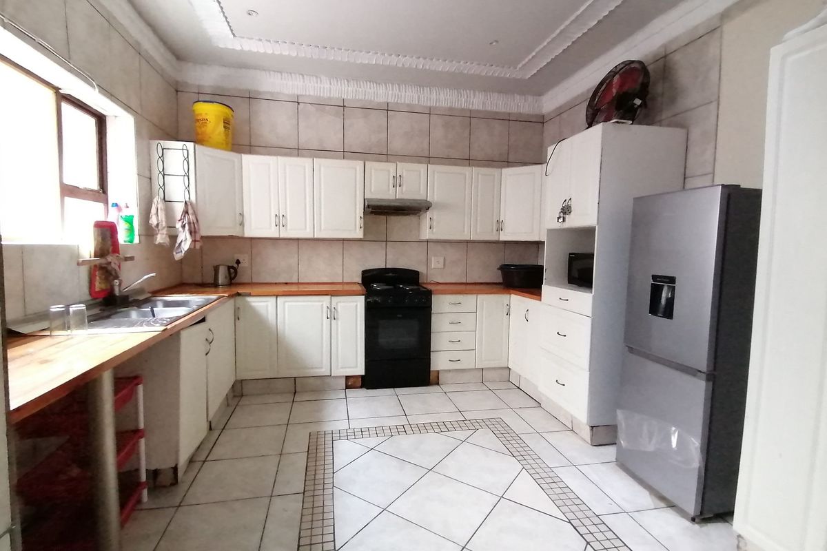 A functional kitchen featuring white cabinetry, wooden countertops, tiled flooring, and a built-in extractor fan.