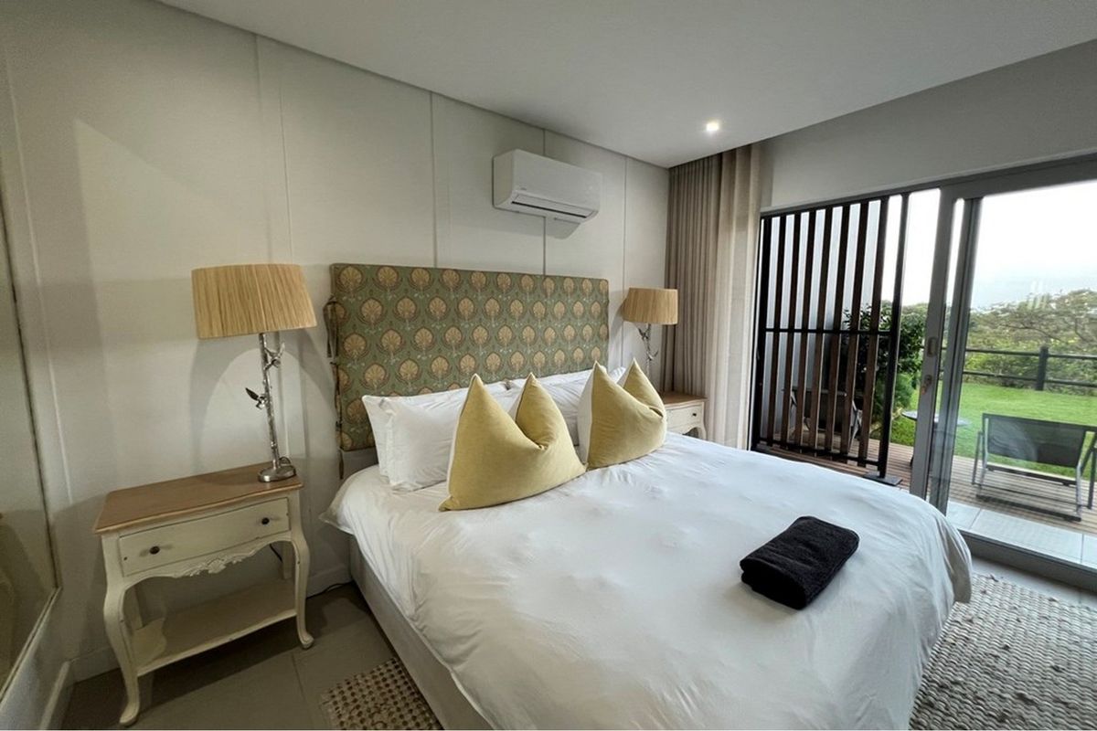 A well-maintained bedroom featuring an air conditioning unit, recessed lighting, and large sliding glass doors that open onto a private balcony.
