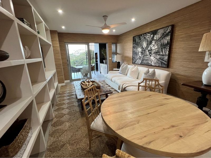 Open-plan living and dining area featuring built-in shelving, textured wall finishes, and sliding glass doors leading to an outdoor patio.