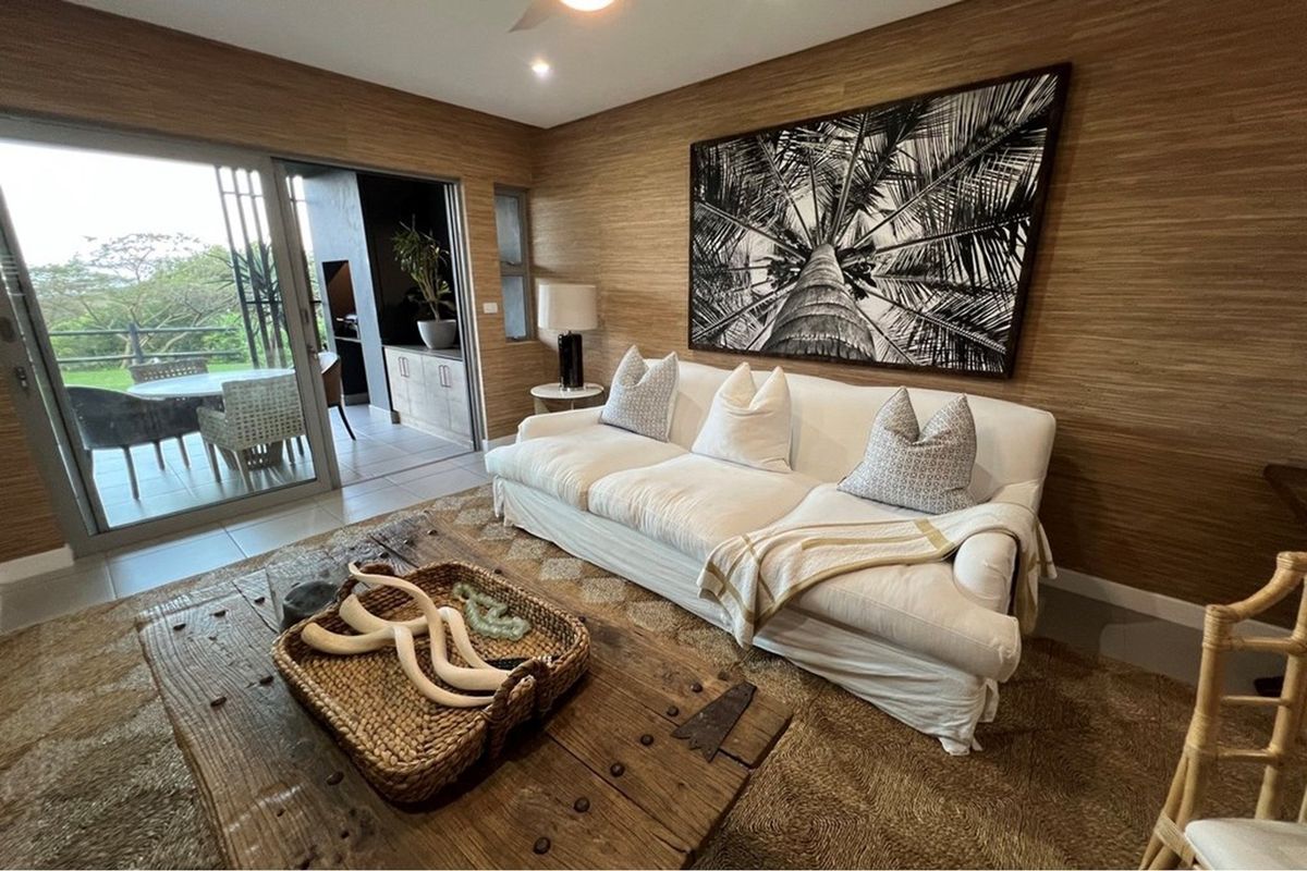 A well-appointed living room featuring textured wall finishes, recessed lighting, and large sliding glass doors that provide seamless access to the outdoor patio area.