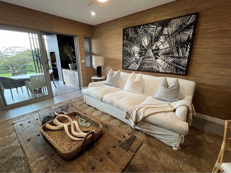 A well-appointed living room featuring textured wall finishes, recessed lighting, and large sliding glass doors that provide seamless access to the outdoor patio area.