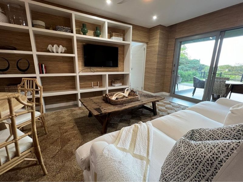 A well-appointed living room featuring custom built-in shelving, textured wall finishes, and large sliding glass doors that provide seamless access to the outdoor area.