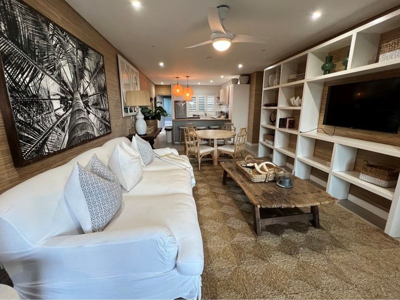 An open-plan living and dining area featuring built-in shelving, textured wall finishes, recessed lighting, and a functional kitchen space with an island.