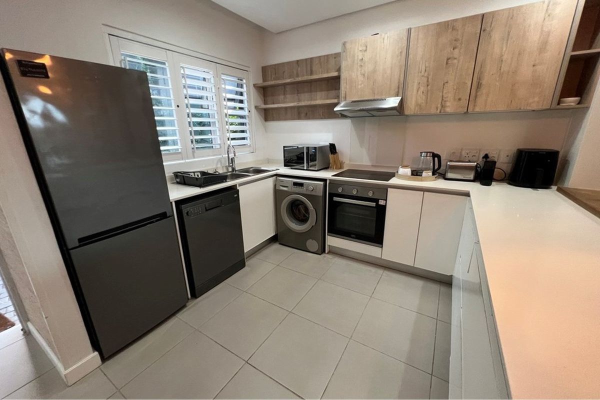 Modern kitchen featuring sleek white and wood-tone cabinetry, stone countertops, integrated appliances, and tiled flooring with functional shutter blinds.