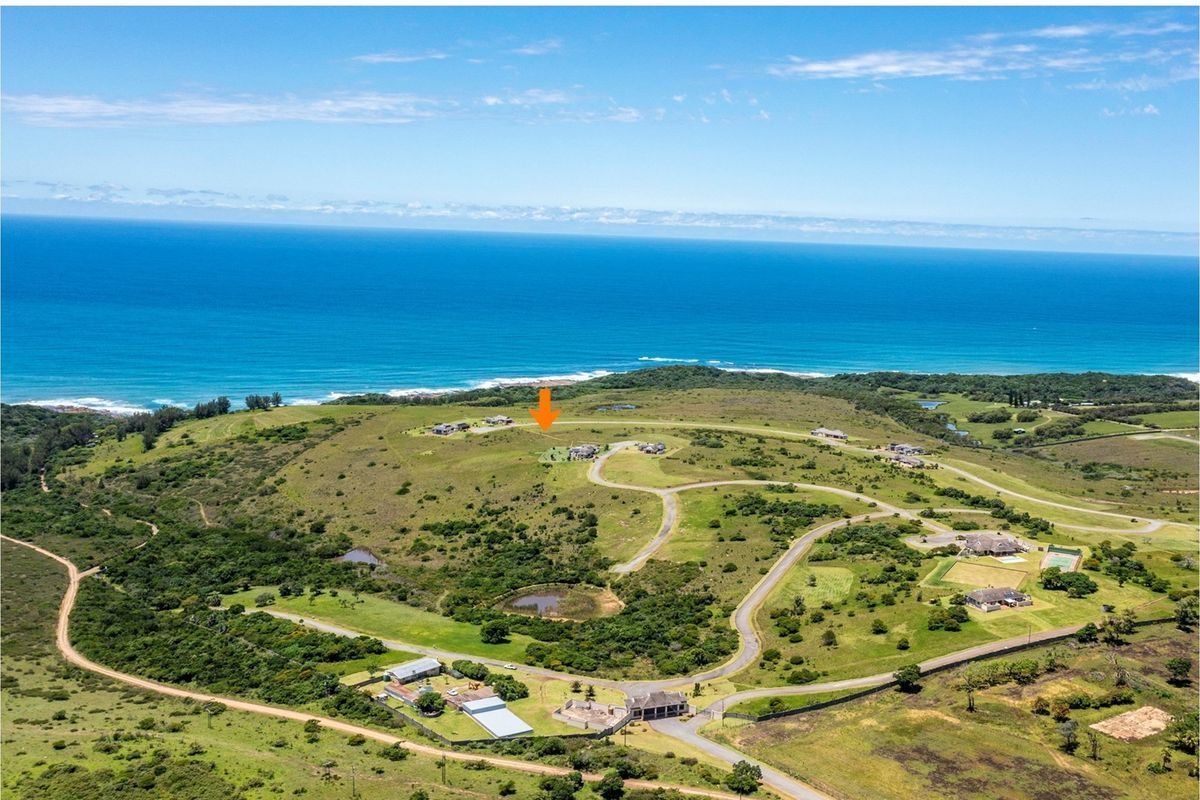 An aerial view of a coastal residential estate featuring rolling hills, established road infrastructure, and proximity to the ocean.
