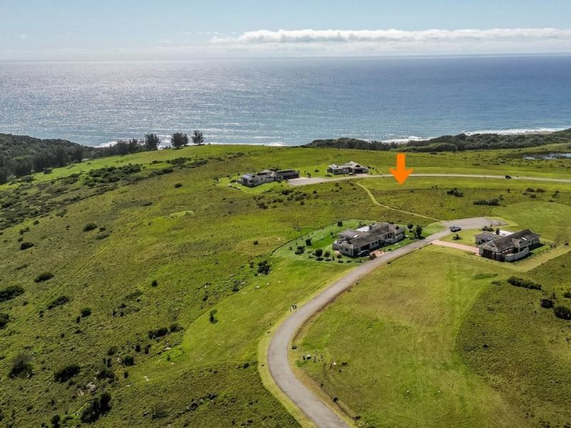Aerial view of a vacant residential plot situated in a coastal estate, featuring expansive ocean views and established road access.
