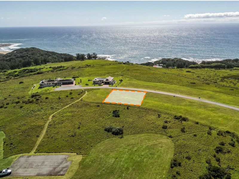 An aerial view of a vacant residential plot situated in a coastal estate with scenic ocean views and established road access.