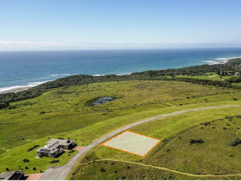 Aerial view of a vacant residential plot featuring coastal proximity and established road access within a scenic landscape.