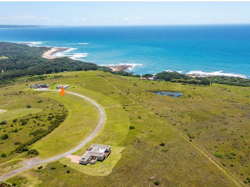 Aerial view of a coastal residential development site featuring paved road access and expansive ocean views.