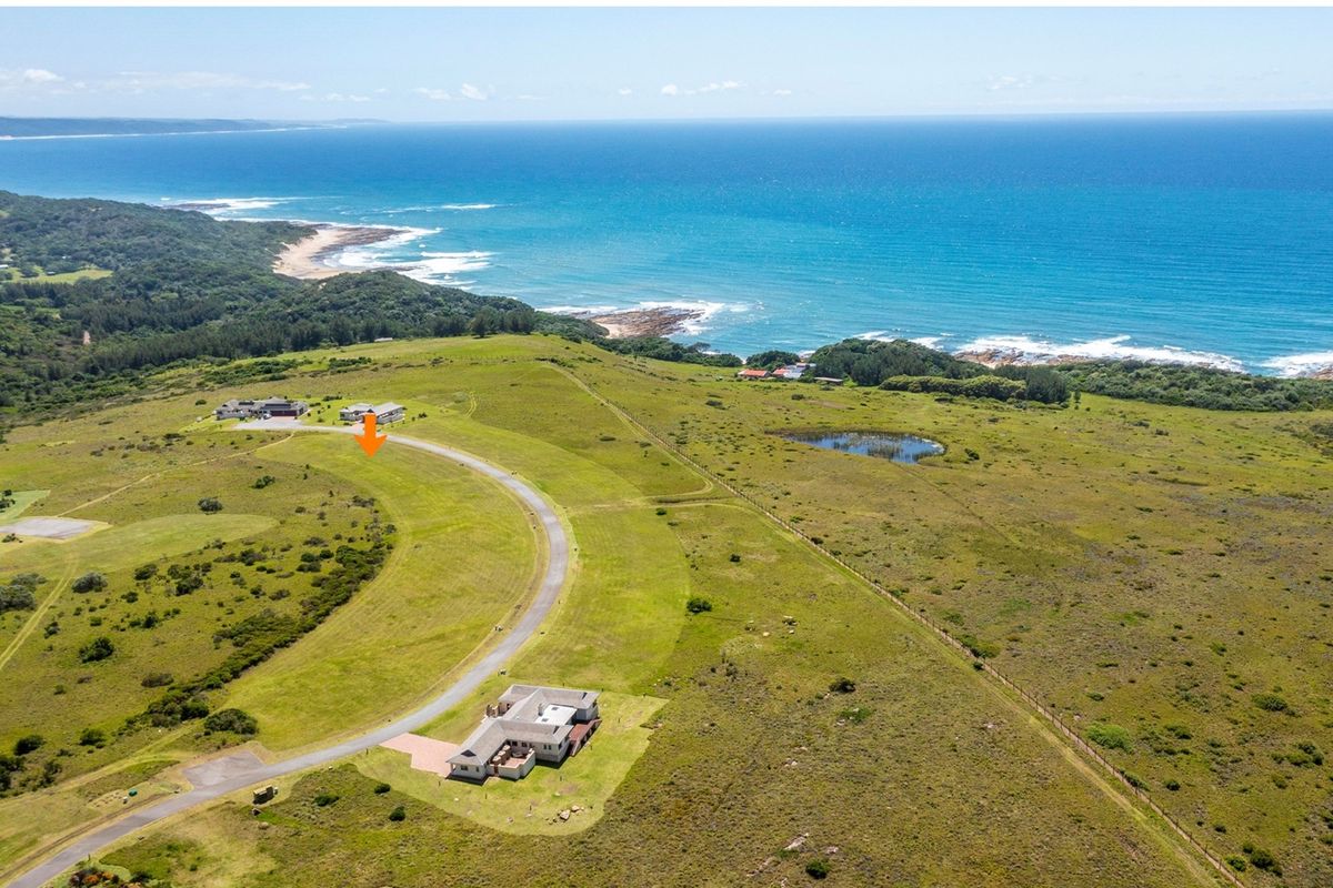 Aerial view of a coastal residential development site featuring paved road access and expansive ocean views.