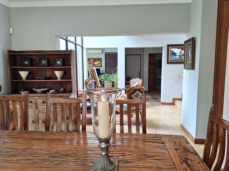 An open-plan living and dining area featuring tiled flooring, coving, and a view through to the hallway and staircase.
