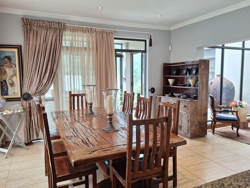 A well-lit dining room featuring tiled flooring, crown molding, and large sliding glass doors that provide access to the outdoor area.