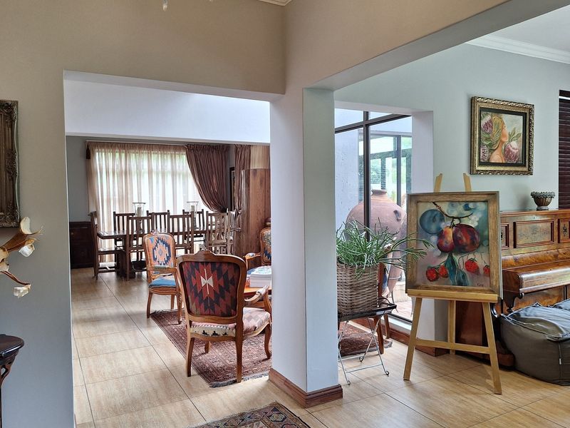 Spacious open-plan living and dining area featuring tiled flooring, large windows, and a skylight, creating a bright and airy atmosphere.