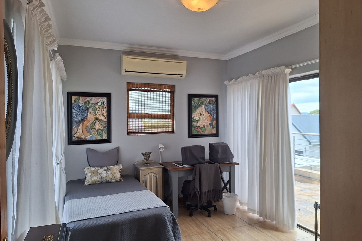 A well-maintained bedroom featuring tiled flooring, crown molding, a split-system air conditioner, and a sliding glass door providing access to an outdoor balcony.