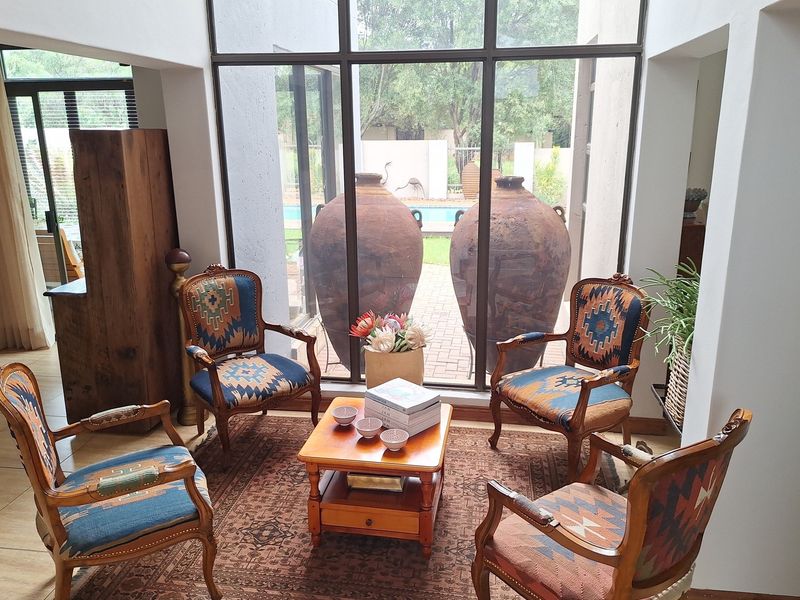 A bright living area featuring large floor-to-ceiling windows that provide natural light and a view of the outdoor pool area.