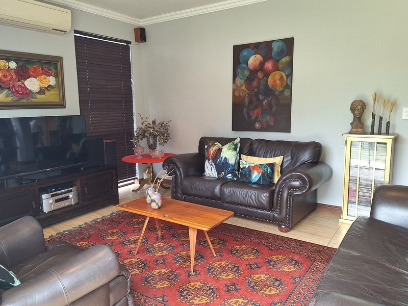 A comfortable living room featuring tiled flooring, coving, and a wall-mounted split-system air conditioner.