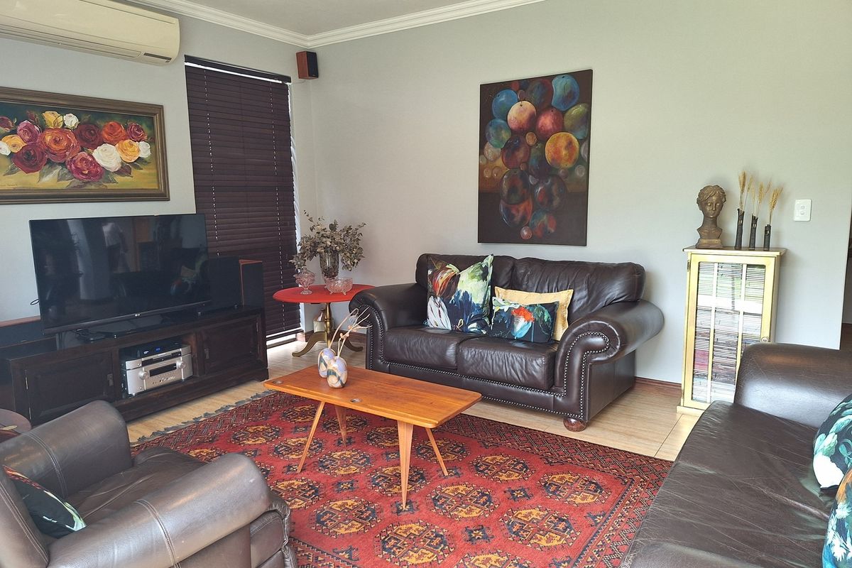 A comfortable living room featuring tiled flooring, coving, and a wall-mounted split-system air conditioner.