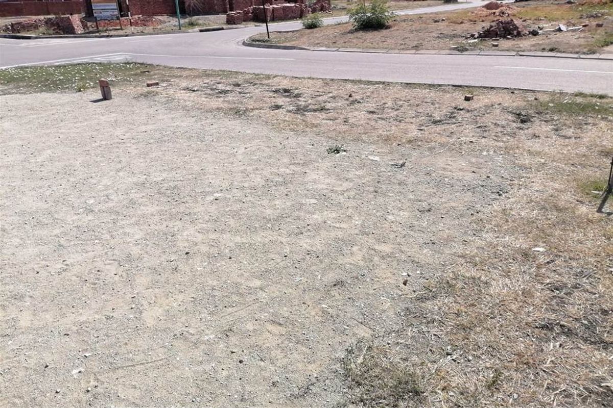 A view of a vacant residential plot showing the street frontage and surrounding undeveloped land.