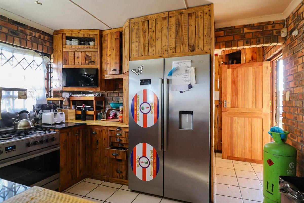 Rustic kitchen featuring exposed brick walls, custom timber cabinetry, tiled flooring, and a built-in gas stove, offering a warm and character-filled cooking space.