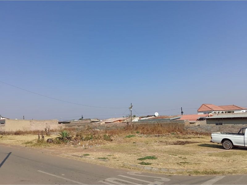 A vacant residential plot featuring a boundary wall and street access, situated in a developed neighborhood.