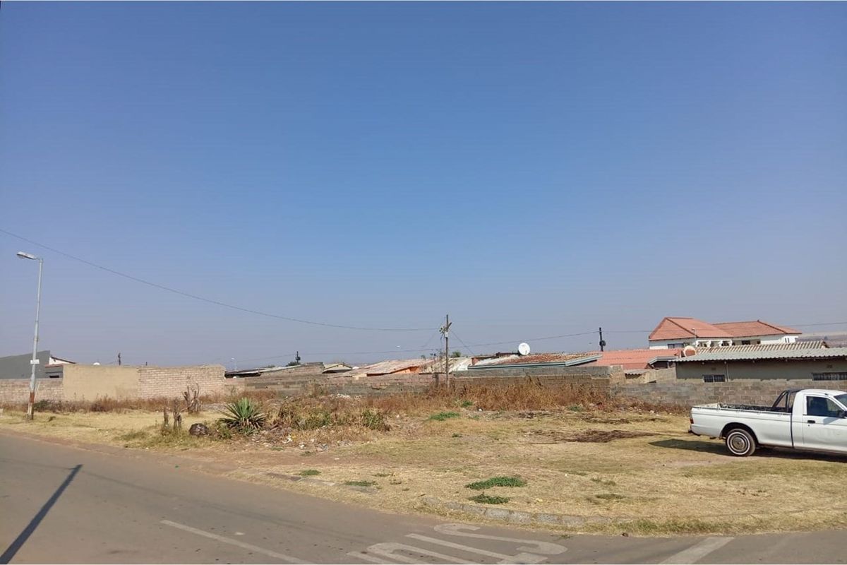 A vacant residential plot featuring a boundary wall and street access, situated in a developed neighborhood.