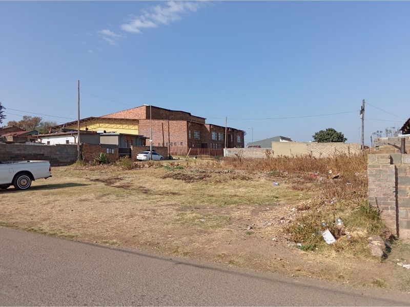A vacant residential plot featuring a level surface, boundary walls, and direct street access in an established neighborhood.