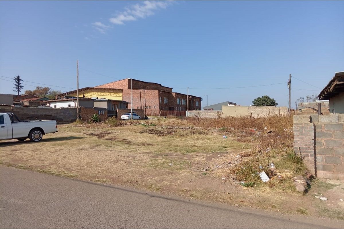 A vacant residential plot featuring a level surface, boundary walls, and direct street access in an established neighborhood.