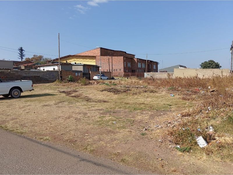 A vacant residential plot featuring street access and perimeter boundary walls, situated in an established neighborhood setting.