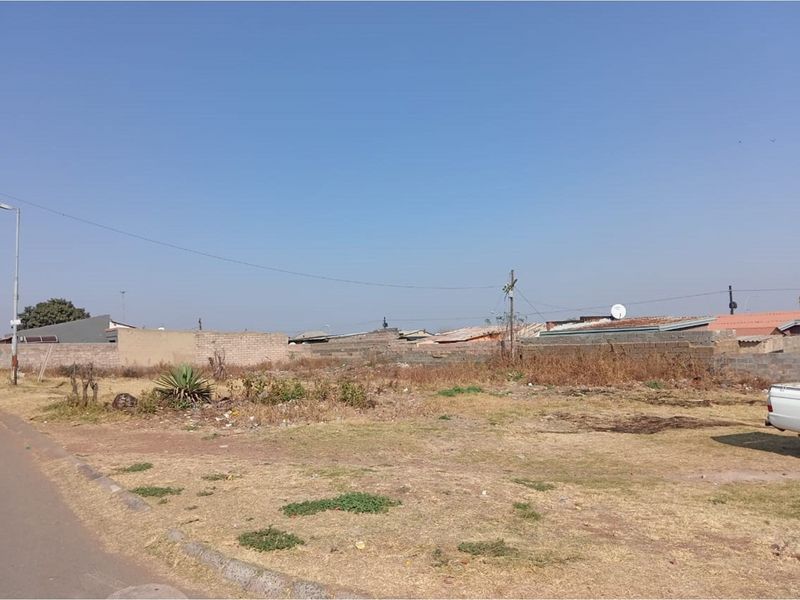 A vacant residential plot featuring perimeter walling and street-side access, offering a blank canvas for future development.
