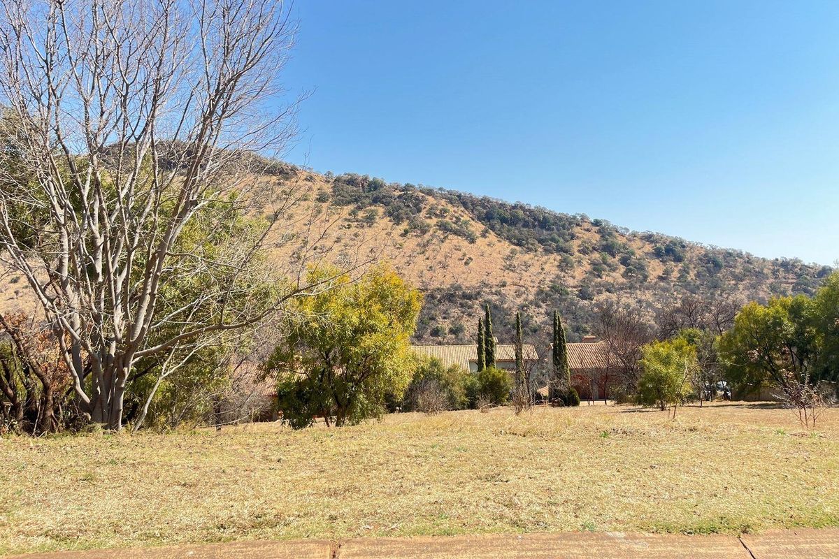 A scenic view of the surrounding landscape featuring mature trees and a prominent mountain backdrop, showcasing the natural setting of the residential land.