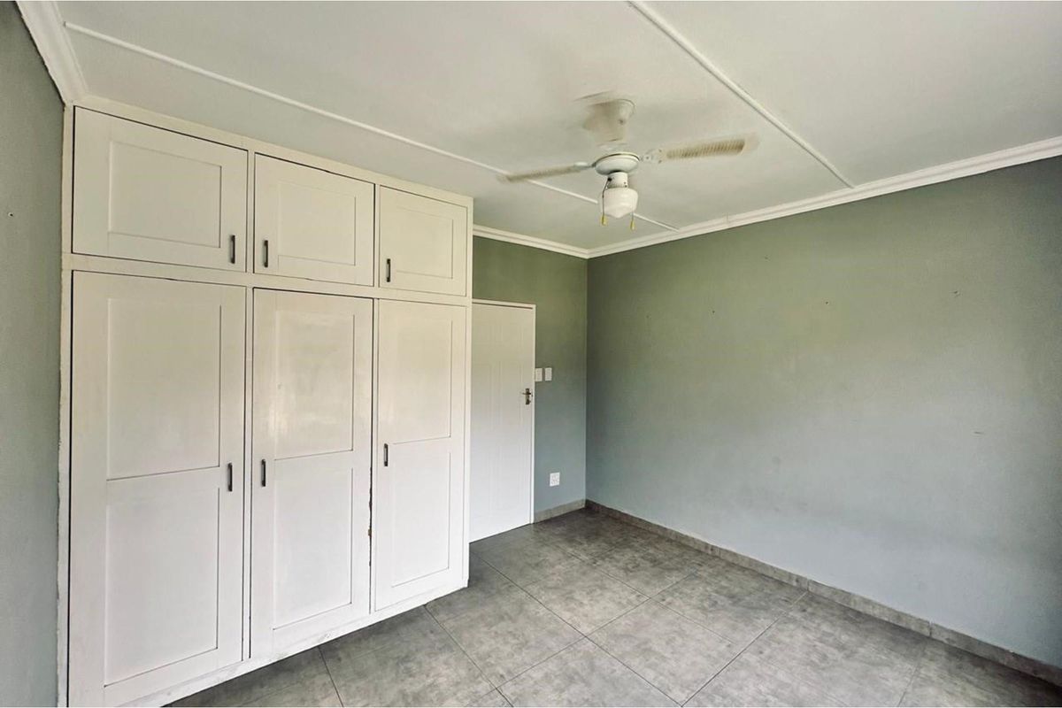 A bedroom featuring built-in white cabinetry, tiled flooring, and a ceiling fan, offering a clean and functional living space.