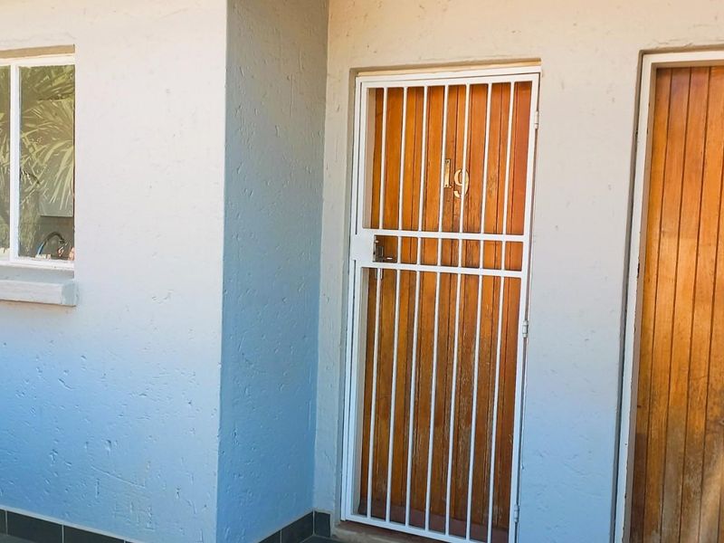 Front entrance area of the townhouse featuring a secure metal gate, timber door, and aluminium window frame.