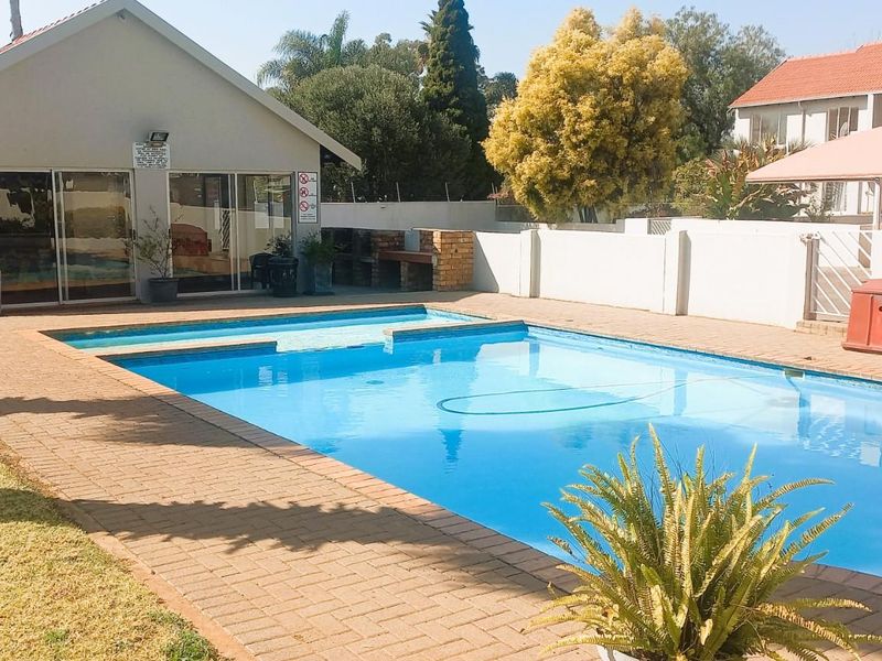 Communal swimming pool area featuring brick paving, a built-in braai, and perimeter walling within a townhouse complex.