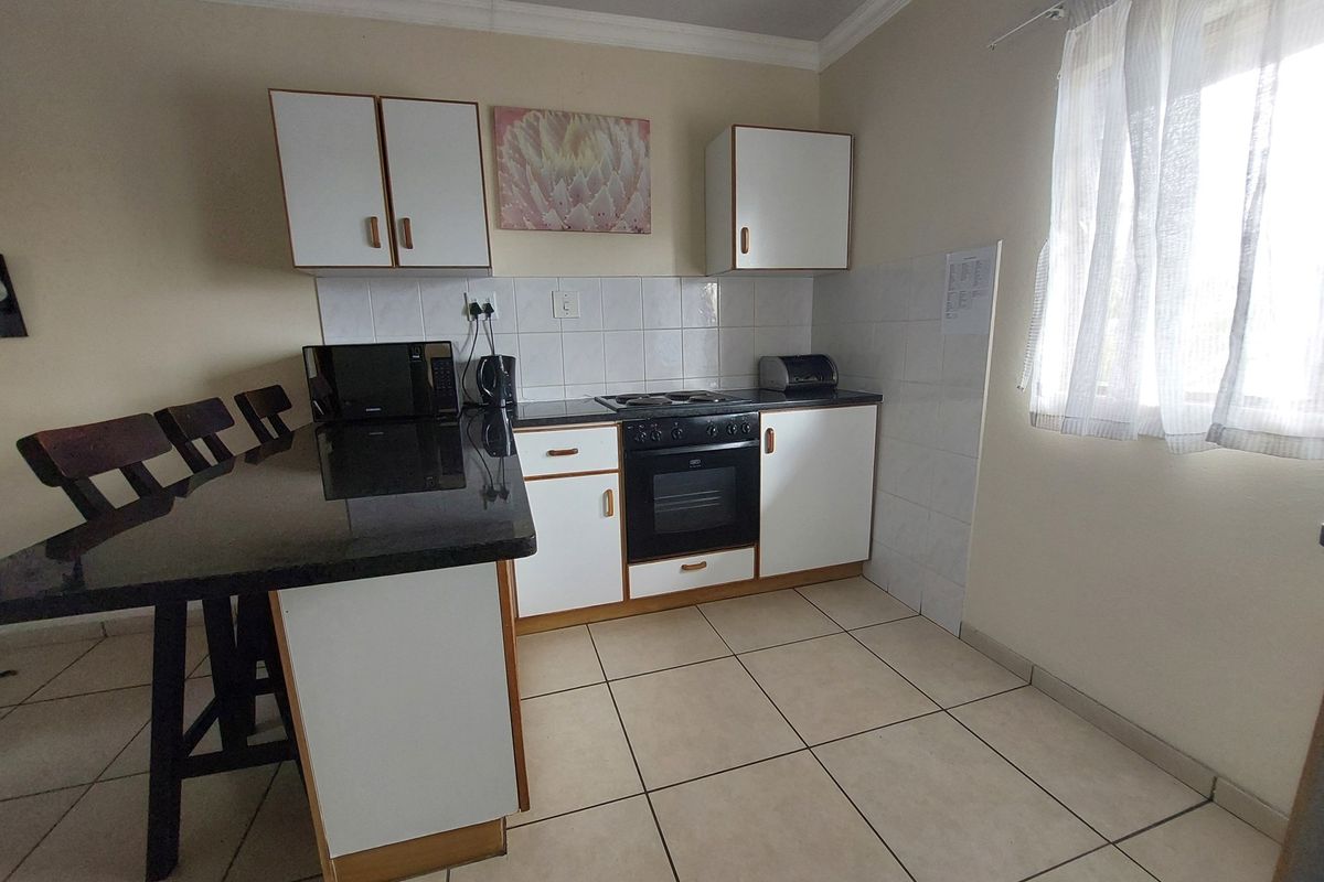 A functional kitchen featuring white cabinetry, a black countertop, a built-in oven with hob, and tiled flooring.