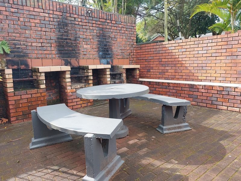 Outdoor entertainment area featuring a built-in brick braai and integrated concrete seating within a private courtyard setting.