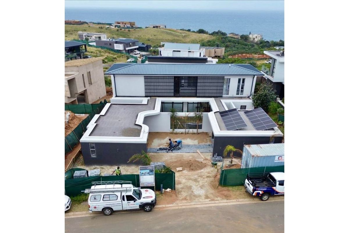 Aerial view of a modern residential property under construction, featuring a flat roof design, solar panels, and a central courtyard area.