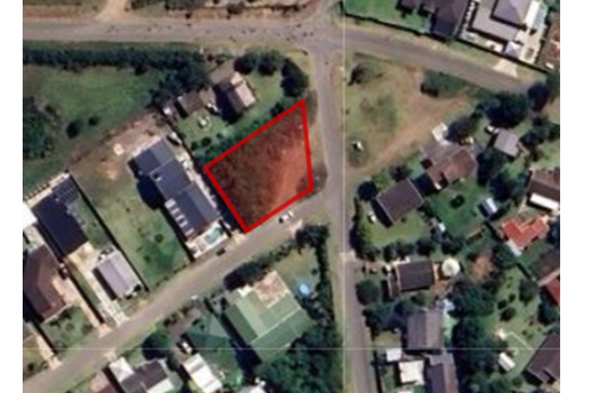 Aerial view of a vacant residential plot highlighted in red, situated within an established suburban neighborhood with surrounding homes and street access.