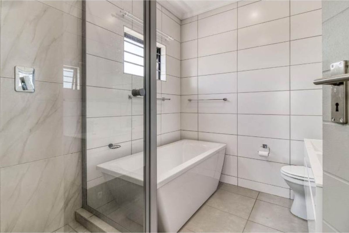 Modern bathroom featuring a built-in bathtub, glass shower enclosure, and tiled walls.