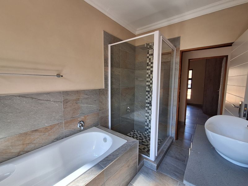 Modern bathroom featuring a tiled bathtub, a separate glass-enclosed shower, and a contemporary vessel sink vanity.