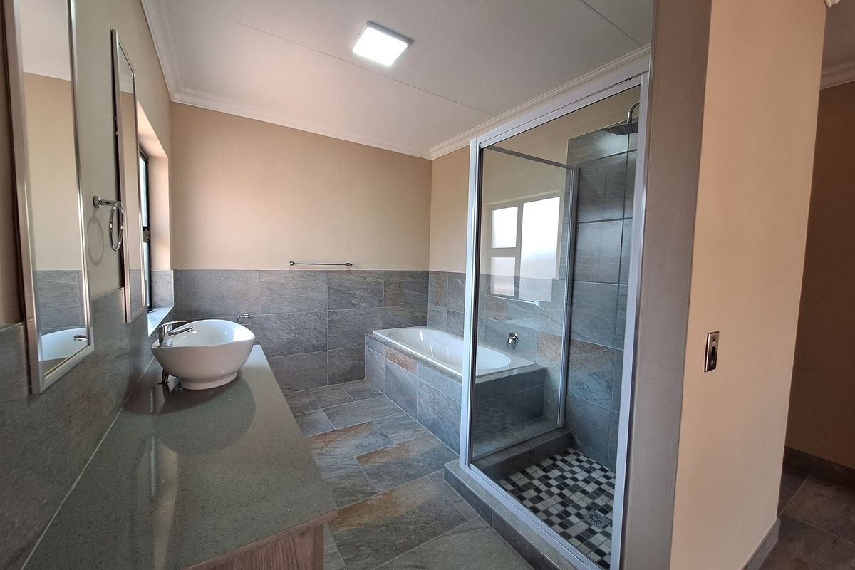 Modern bathroom featuring a tiled walk-in shower, a built-in bathtub, and a vanity with a vessel sink.