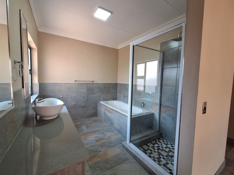 Modern bathroom featuring a tiled walk-in shower, a built-in bathtub, and a vanity with a vessel sink.