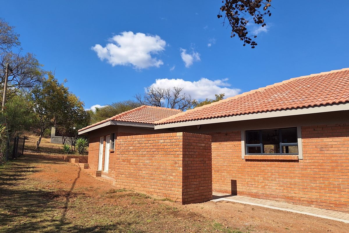 A view of the rear exterior of the house, featuring face brick walls, a tiled roof, and paved pathways.