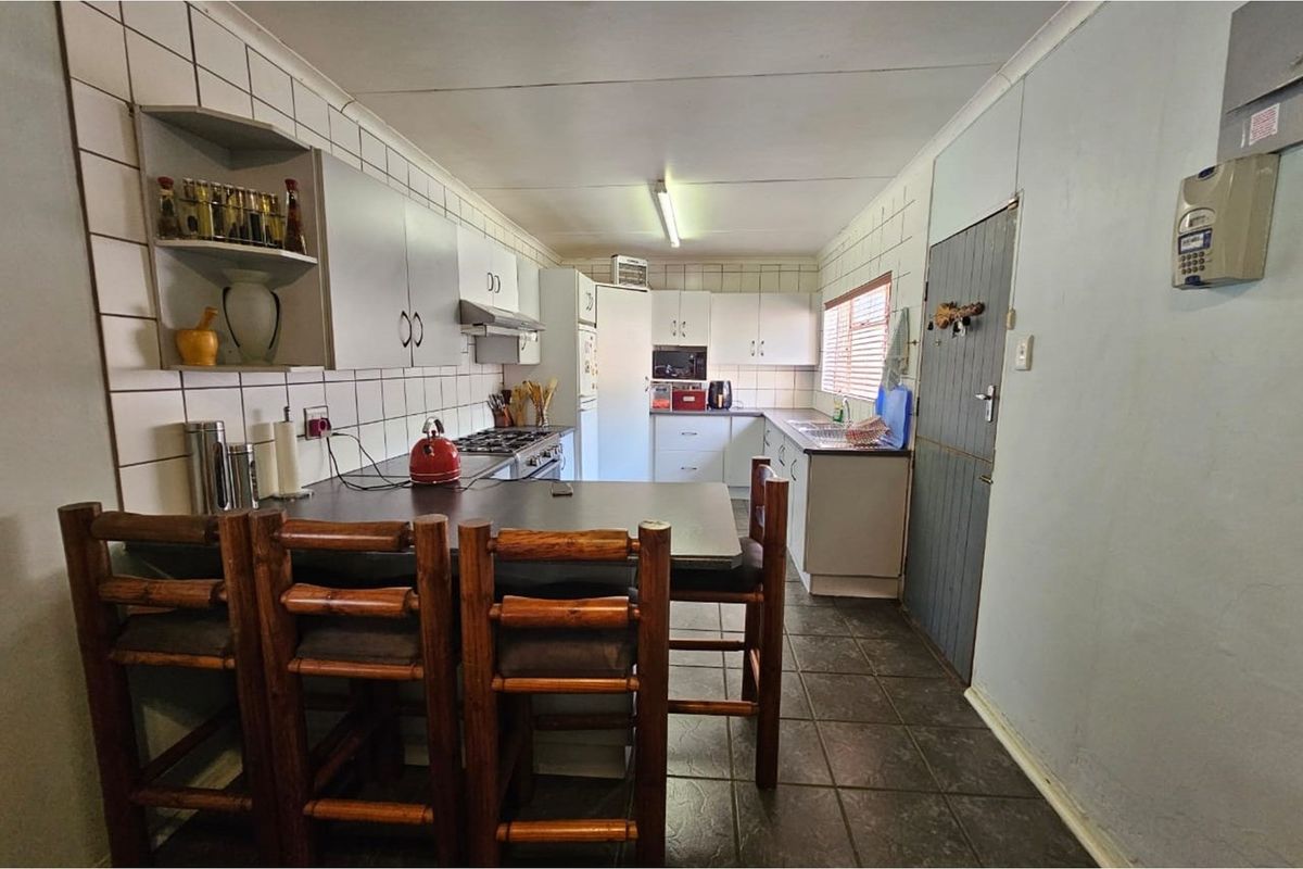 Functional kitchen featuring built-in cabinetry, tiled splashbacks, integrated stove and extractor fan, and a breakfast bar area.