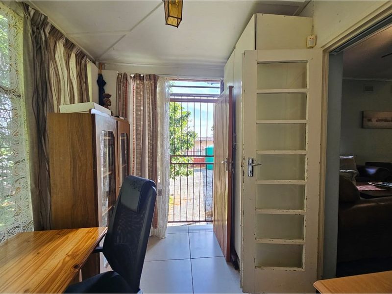 A functional office space featuring tiled flooring, built-in storage, and direct access to an outdoor area through a security gate.