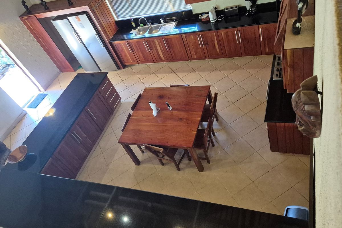 Spacious kitchen featuring dark granite countertops, extensive wooden cabinetry, and a central dining area with tiled flooring throughout.