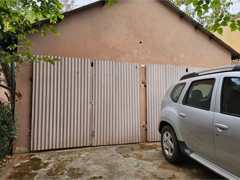 Exterior view of a detached garage featuring corrugated metal doors and a concrete driveway area.