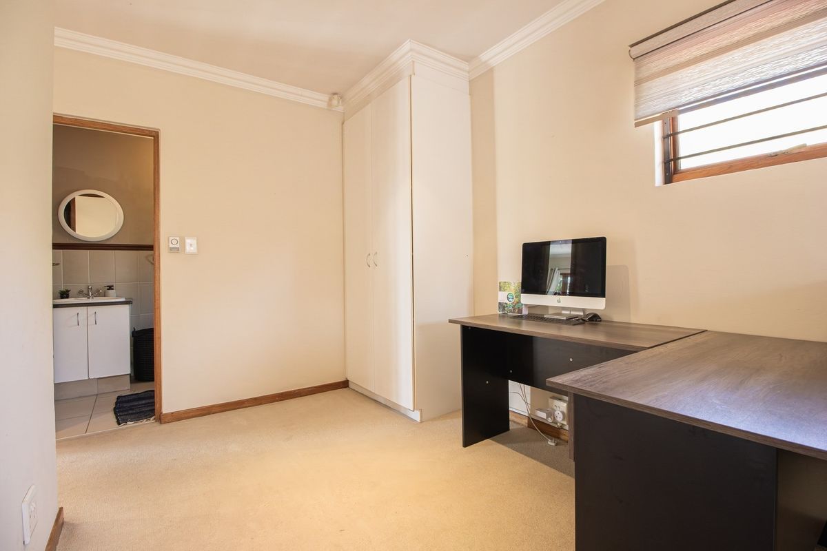A bedroom featuring neutral walls, carpet flooring, a built-in wardrobe, and an attached en-suite bathroom with a vanity.