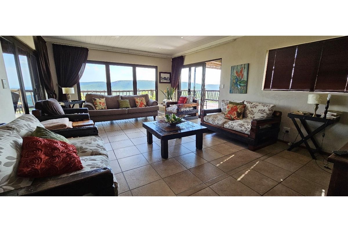 Spacious living room featuring large sliding glass doors that open to a scenic outdoor view, complemented by neutral tiled flooring and recessed ceiling lighting.